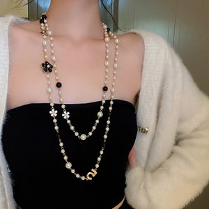 A FAUX PEARL NECKLACE AND A CAMELLIA BROOCH