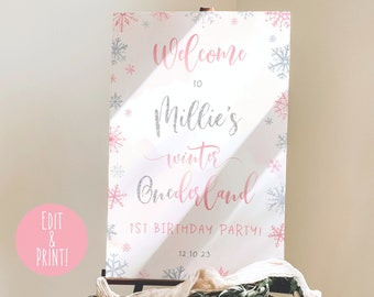 May include: A pink and silver printable sign that says "Welcome to Millie's Winter Wonderland 1st Birthday Party! 12.10.23". The sign is decorated with snowflakes.