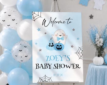 Könnte beinhalten: Ein rechteckiges Willkommensschild für eine Babyparty auf einer Metallstaffelei mit hellblauem Aquarellhintergrund, einem Cartoon-Geist mit blauer Fliege, zwei blauen Kürbissen, Spinnennetzen und Sternen. Der Text lautet: Welcome to ZOEY'S BABY SHOWER 10.27.26.