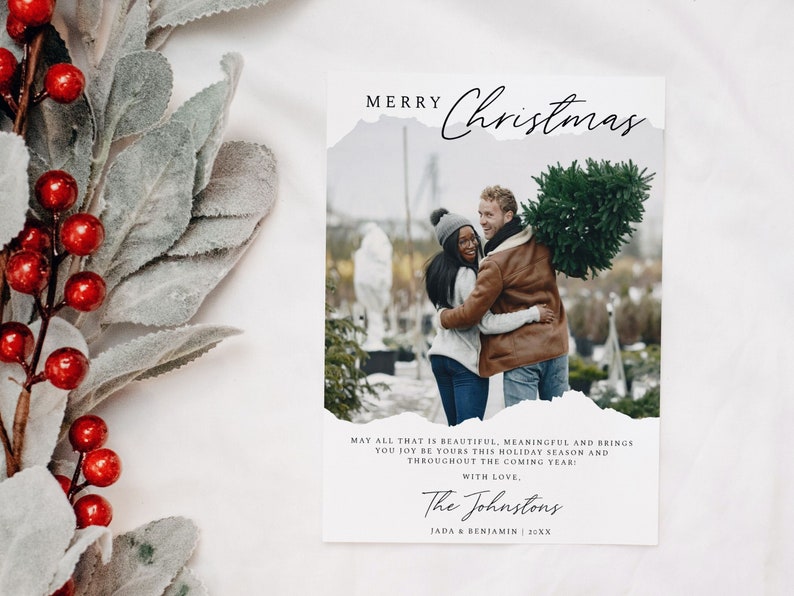 May include: A Christmas card with a photo of a couple holding a Christmas tree. The card has a white background with black text that reads "Merry Christmas" and "May all that is beautiful, meaningful and brings you joy be yours this holiday season and throughout the coming year: With love, The Johnstons JADA & BENJAMIN 20XX".