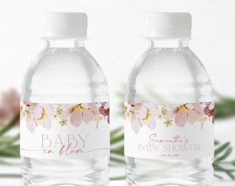 Könnte beinhalten: Zwei durchsichtige Plastikwasserflaschen mit Etiketten, die ein Blumenmuster zeigen. Das Etikett auf der linken Flasche lautet "Baby in Bloom" und das Etikett auf der rechten Flasche lautet "Samantha's Baby Shower 30. Juli 2023".