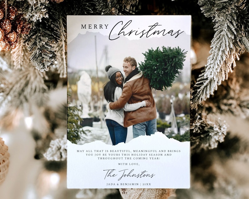 May include: A Christmas card with a photo of a couple holding a Christmas tree. The card has a white background with a blue and white watercolor design. The text on the card reads "Merry Christmas" and "May all that is beautiful, meaningful and brings you joy be yours this holiday season and throughout the coming year! With love, The Johnstons Jada & Benjamin 20XX".