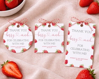 May include: Three white gift tags with red strawberry accents and the text "THANK YOU berry much FOR CELEBRATING WITH ME!" are displayed. The tags are tied with red and white twine. Fresh strawberries are scattered around the tags.