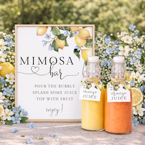 May include: A Mimosa Bar sign with a wooden frame, featuring lemons and blue flowers. Two glass bottles with mango and orange juice are in front of the sign. The sign reads "Mimosa Bar" and instructions.