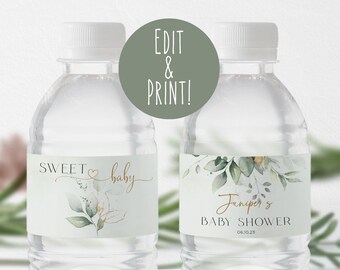 May include: Two clear plastic water bottles with labels. The labels are white with green foliage and gold accents. The text on the labels reads "Sweet baby" and "Juniper's Baby Shower 06.10.23".