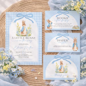 May include: Baby shower stationery set featuring a blue gingham pattern and illustrations of a bunny in a blue jacket. The set includes an invitation, a "Books for Baby" card, a "Diaper Raffle" card, and a "Thank You" card. Text includes the phrase "A Little Bunny is on the Way."