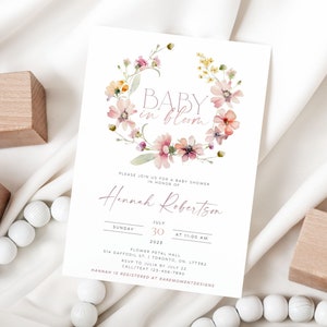 Peut inclure: Une invitation &agrave; une f&ecirc;te pr&eacute;natale avec une couronne florale aquarelle et le texte "BABY in bloom". L'invitation est pour Hannah Robertson et est pr&eacute;vue pour le dimanche 30 juillet 2025 &agrave; 11h00. Le lieu est Flower Petal Hall, 514 Daffodil St., Toronto, ON L1T5B2. RSVP &agrave; Julia avant le 22 juillet, appeler/envoyer un SMS au 123-456-7890. Hannah est inscrite chez RareMomentDesigns.