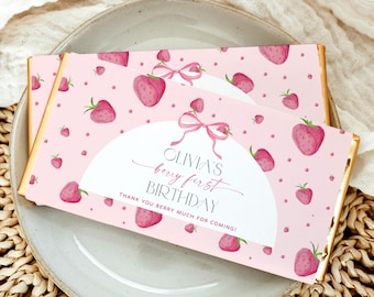 May include: Pink and white chocolate bar wrapper with a strawberry pattern. The wrapper has the text "Olivia's berry first birthday" and "Thank you berry much for coming!"