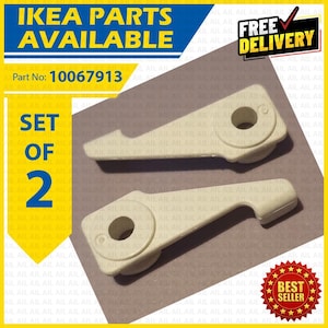 Puede incluir: Un juego de dos piezas de repuesto IKEA de plástico color blanco roto, identificadas con el número de pieza 10067913. Cada pieza presenta un orificio circular en un extremo y un brazo curvo y cónico, diseñado para el montaje de muebles.
