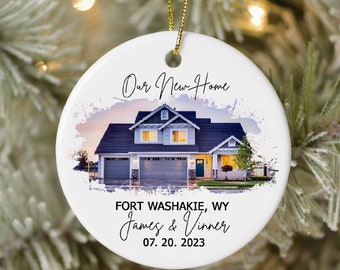 May include: A white ceramic Christmas ornament with a watercolor-style image of a house. The text "Our New Home" is written in black script at the top of the ornament. Below the image, the text reads "Fort Washakie, WY James & Vinny 07.20.2023".