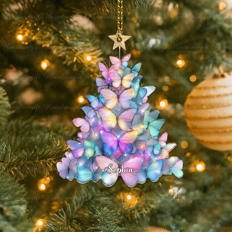 May include: A Christmas tree ornament shaped like a tree, made of colorful butterflies. The butterflies are in shades of pink, blue, purple, and yellow. The name "Sophia" is written on the ornament. A gold star hangs from the top.