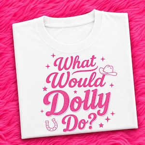 May include: A white short-sleeved t-shirt featuring the pink text What Would Dolly Do? in a stylized font. The design includes a small pink cowboy hat icon, a horseshoe icon, and several four-pointed star accents surrounding the lettering.
