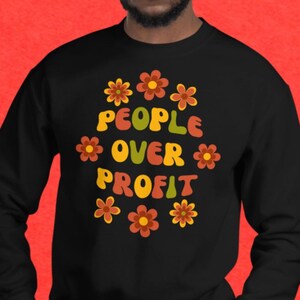 May include: Black sweatshirt with a retro-style graphic that says "People Over Profit" surrounded by colorful flowers.