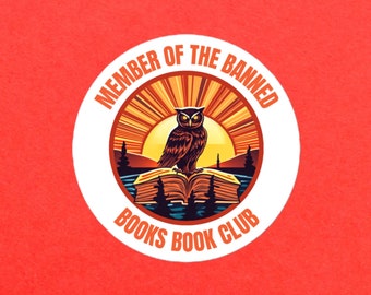 May include: A white circle with the text "Member of the Banned Books Book Club" around the edge. Inside the circle is an illustration of an owl perched on a book with a sunset in the background.