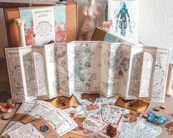 Peut inclure: Une collection d'objets sur le thème de la fantasy, comprenant une carte, des autocollants, une petite bouteille et une boîte avec le titre "Throne of Glass" en espagnol. Les objets sont disposés sur une table en bois avec des feuilles d'automne et de petits cercles en bois.