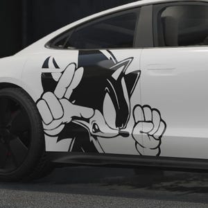 May include: White sports car with black wheels and a black and white cartoon character graphic on the side. The car has a sleek design with red brake calipers visible through the wheels.