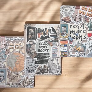 May include: Three decorated notebooks with a book and reading theme. The notebooks have a variety of stickers, including a cat, a globe, a stack of books, and a quote that says "Read More Books".