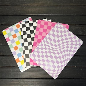 May include: Four checkered patterned cards in different colors. The cards are pink, black and white, light blue and orange, and purple. The cards are arranged in a fan shape.