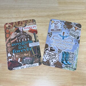 May include: Two colorful wooden cutting boards with a collage of images and text. The first board has a saloon theme with the text "Texas cowgirls live forever" and "Ride 'em Cowgirl!" The second board has a denim theme with the text "How leads to Hollerin'" and "Grab life by the horns".