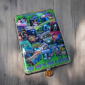 Könnte beinhalten: Eine grüne und violette Tablethülle mit einer Collage von Goosebumps-Buchcovern. Die Hülle trägt den Text "Reader Beware" und "You are in for a scare".