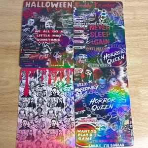 May include: Four rectangular Halloween-themed cards with various horror movie characters and text. The cards feature images of Freddy Krueger, Michael Myers, and Ghostface. Text includes "Halloween," "Freddy Krueger," and "Horror Queen."