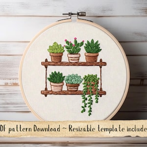 May include: Embroidered hoop art featuring a wooden shelf with six potted succulents in various shades of green and pink. The design is set against a cream-colored fabric, held within a wooden embroidery hoop. Text at the bottom reads "PDF pattern Download ~ Resizable template included."