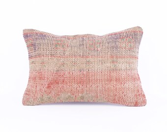 May include: A rectangular cushion with a woven fabric cover. The cushion has a pink, beige and blue pattern with a subtle geometric design.