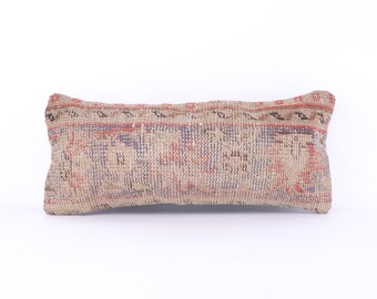 May include: A long, rectangular pillow with a beige background and a colorful, intricate pattern. The pattern features shades of red, blue, and black, creating a traditional and ethnic design.
