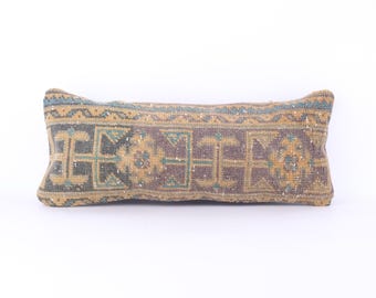 May include: A long, rectangular cushion with a woven pattern in shades of brown, beige, and blue. The cushion has a traditional, geometric design.