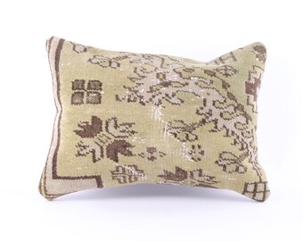 May include: A green and brown patterned throw pillow with a floral design. The pillow is made of a soft, woven fabric.
