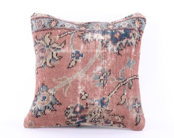 May include: A pink and blue patterned throw pillow with a floral design. The pillow is made from a woven fabric and has a frayed edge.