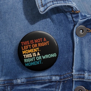 May include: A black button with a rainbow colored text that reads "This is not a left or right moment. This is a right or wrong moment."
