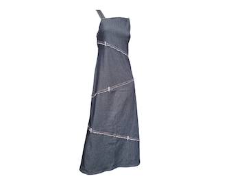 Può includere: Un abito lungo in denim scuro con una sola spallina. L'abito presenta cuciture diagonali con bordi sfilacciati e un accento rosa chiaro. L'abito è di colore blu scuro e ha una gonna lunga e fluida.