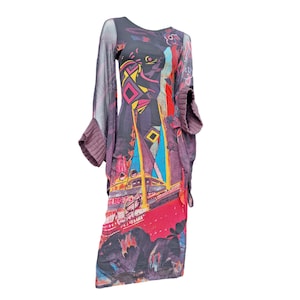 May include: A long, colorful dress with a unique design. The dress features a mix of geometric shapes and abstract patterns in shades of red, blue, yellow, and purple. It has long sleeves with knitted cuffs and a sheer overlay.
