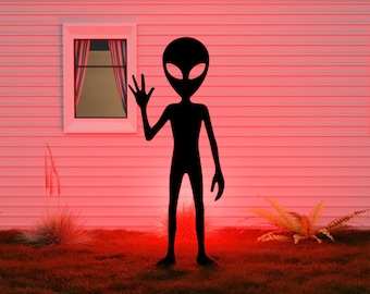 May include: A black silhouette of an alien figure waving in front of a white house with windows. The scene is illuminated with a red glow, creating a mysterious and otherworldly atmosphere. Green grass and plants are in the foreground.