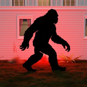May include: A black silhouette of a Bigfoot figure walking across a grassy lawn in front of a white house with windows. The scene is illuminated with a red glow, creating a mysterious and eerie atmosphere. The image evokes a sense of the unknown and the outdoors.