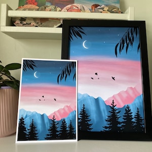 May include: Two framed paintings depicting a night sky with a crescent moon, stars, and a pink and blue mountain range with a silhouette of trees in the foreground.