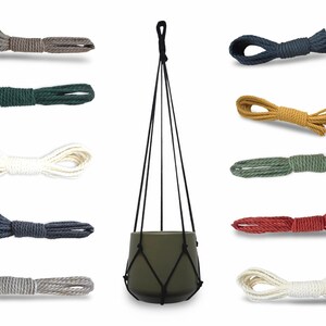 May include: A central olive green ceramic plant pot held by a black macrame rope hanger, surrounded by ten individual coiled rope samples in various colors including grey, dark green, cream, navy, tan, sage, red, and off-white.