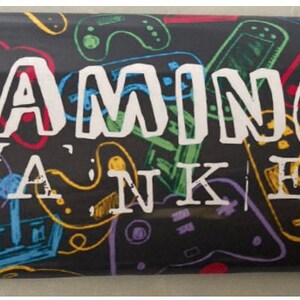 Puede incluir: Una bolsa de regalo de temática de juegos en blanco y negro con las palabras "GAMING WANKER" impresas en blanco en la parte delantera.