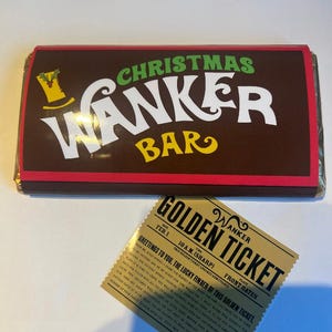 May include: A brown chocolate bar with the text "CHRISTMAS WANKER BAR" in white and yellow. A golden ticket with the text "GOLDEN TICKET" and "WANKER" is next to the bar. The ticket has text that is difficult to read.