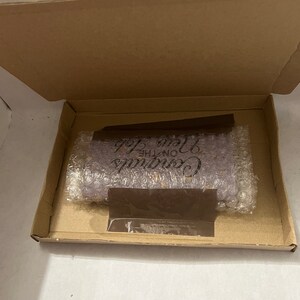May include: A purple soap bar with the text "Continue on the Love Path" in black lettering. The soap bar is packaged in a brown cardboard box with bubble wrap.