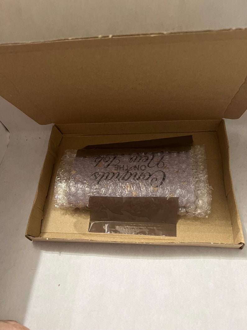 May include: A purple soap bar with the text "Continue on the Love Path" in black lettering. The soap bar is packaged in a brown cardboard box with bubble wrap.