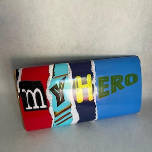 May include: A red, blue, yellow, and green box with the word "MYHERO" printed on it. The letters are in a stylized font and are partially obscured by torn edges.