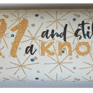 Könnte beinhalten: Eine weiße Schokoladentafel mit goldenen Glitzer und einem schwarzen und goldenen Design. Der Text auf der Tafel lautet "21 and still a knob".