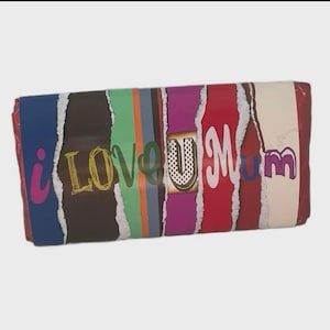 Op de afbeelding: Een rechthoekige geschenkdoos met een kleurrijk, gescheurd papierontwerp. De doos heeft verticale strepen in blauw, bruin, groen, grijs, paars, rood en crème. De tekst op de doos luidt "i LOVE U mum" in verschillende lettertypen en kleuren.
