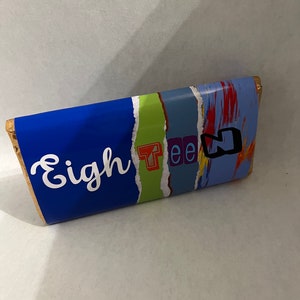 May include: A blue and colorful chocolate bar wrapper with the word "Eighteen" printed on it.