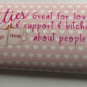 Op de afbeelding: Roze chocoladeverpakking met witte hartjes en de tekst "Besties Great for love & support & bitching about people!" met twee mokken waarop "Best Friend" staat.