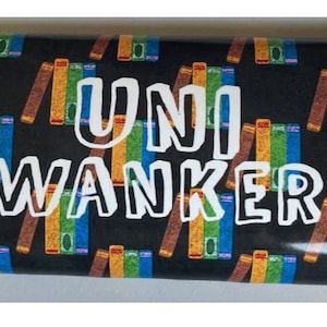 May include: A chocolate bar wrapped in gold foil with a black background and a pattern of colorful books. The text "UNI WANKER" is printed in white on the front of the bar.