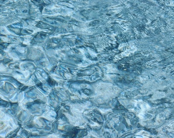 Pode incluir: Um close-up de água azul ondulada com um tom azul claro. A água é clara e reflete a luz, criando um efeito cintilante.