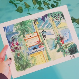 May include: A watercolor painting of a building with a yellow door and a sign that reads "Today's Special is..." in Japanese. The building is surrounded by green plants and flowers. A black cat is sitting on a windowsill.